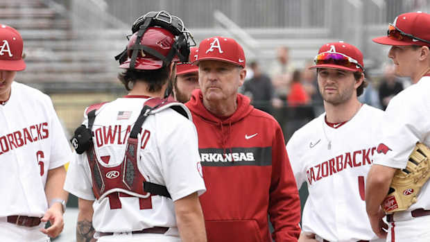 Arkansas Razorbacks coach Dave Van Horn talking with catcher Parker Rowland waiting on relief pitcher Koty Frank.